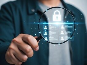 A person holding a magnifying glass with a digital lock and user icons.